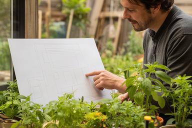 Consulente di giardinaggio che osserva una planimetria accanto a piante in vaso